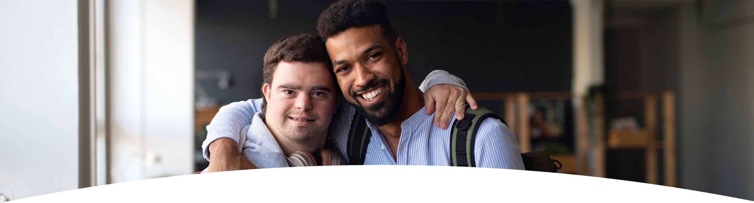 header_ueberuns Junge mit Behinderung und Betreuer umarmen sich