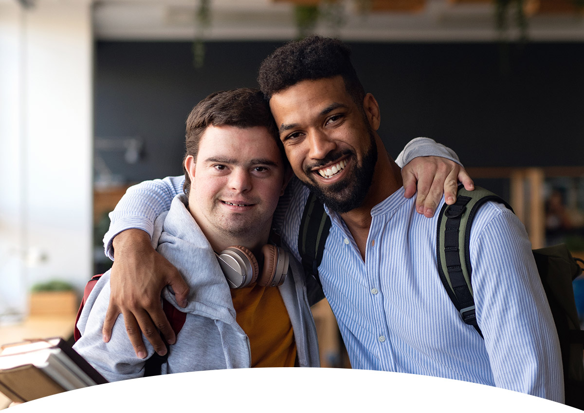 header_ueberuns_mob Junge mit Behinderung und Betreuer umarmen sich